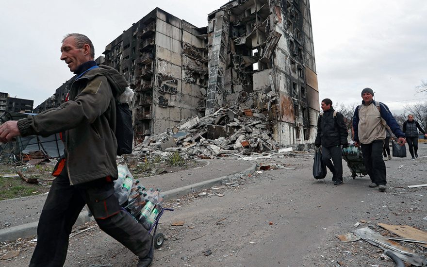 Local residents walk past a building destroyed during Ukraine-Russia conflict in the southern port city of Mariupol, Ukraine April 3, 2022. REUTERS/Alexander Ermochenko